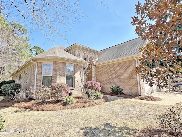 view of front facade with stone siding, an attached garage, brick siding, and roof with shingles