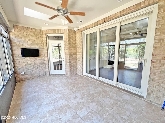 unfurnished sunroom featuring a skylight, a ceiling fan, and visible vents