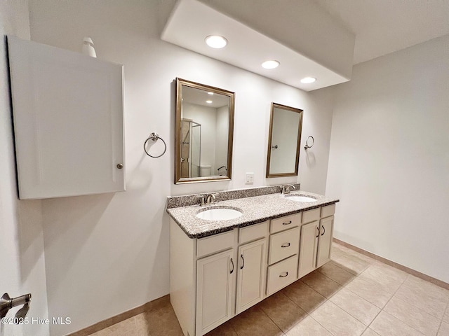 full bathroom featuring double vanity, recessed lighting, baseboards, and a sink