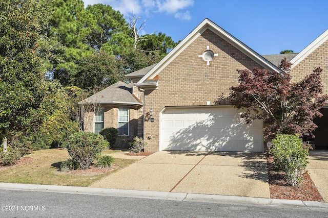 traditional-style home with concrete driveway, an attached garage, brick siding, and a shingled roof