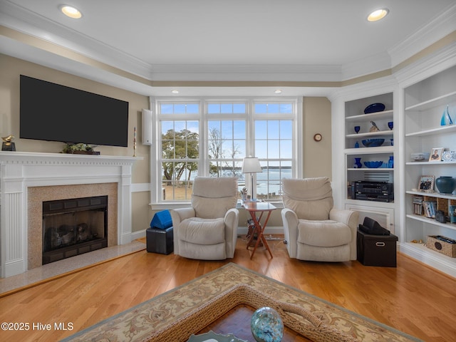 sitting room featuring built in features, a premium fireplace, ornamental molding, hardwood / wood-style floors, and recessed lighting