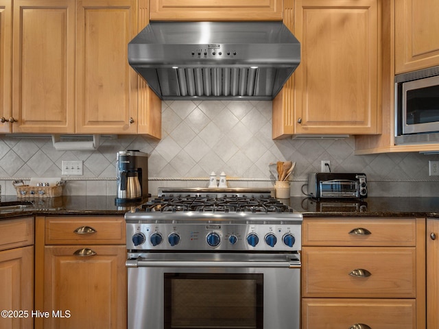 kitchen featuring extractor fan, a toaster, stainless steel appliances, backsplash, and dark stone countertops