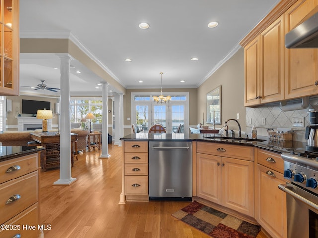 kitchen featuring light wood finished floors, appliances with stainless steel finishes, wall chimney range hood, ornate columns, and ceiling fan with notable chandelier