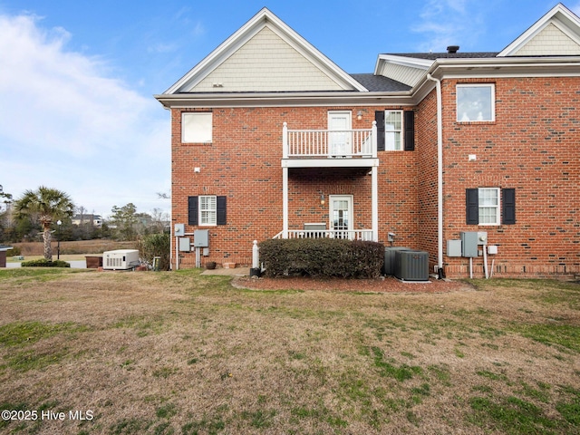 rear view of property with a yard, brick siding, cooling unit, and a balcony