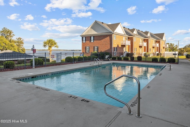 pool with a patio area, fence, and a residential view