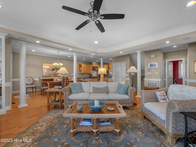 living room with light wood-style floors, recessed lighting, crown molding, and decorative columns