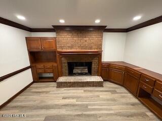 living area featuring a brick fireplace, light wood-style floors, and ornamental molding