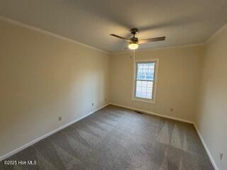 spare room with dark colored carpet, baseboards, ornamental molding, and a ceiling fan