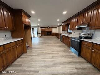 kitchen with stainless steel electric range oven, light wood finished floors, light countertops, and under cabinet range hood