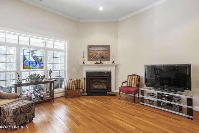 sitting room with crown molding, recessed lighting, a premium fireplace, wood finished floors, and baseboards