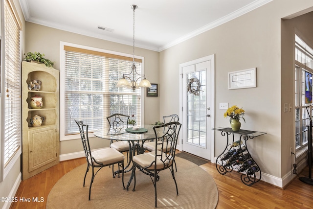 dining room featuring ornamental molding, visible vents, and wood finished floors