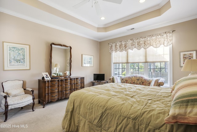 bedroom with ornamental molding, a raised ceiling, visible vents, and light colored carpet