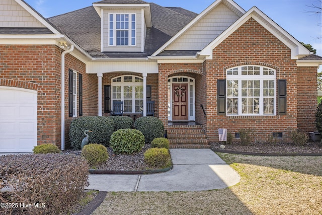 property entrance featuring a shingled roof, crawl space, brick siding, and an attached garage