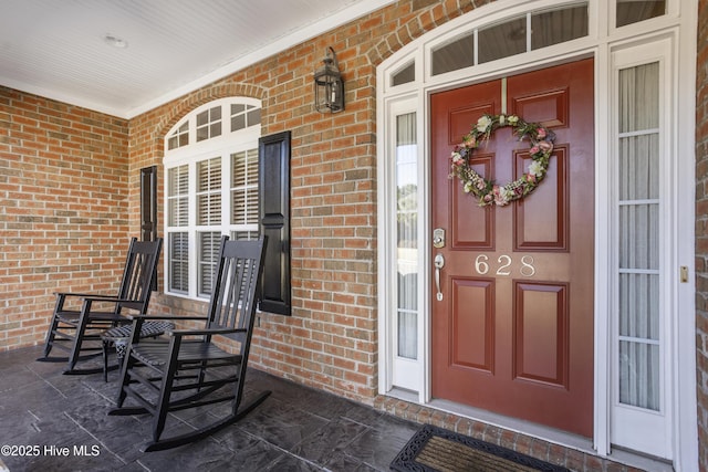 property entrance featuring covered porch and brick siding