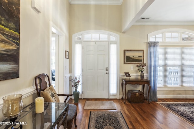 entryway featuring baseboards, visible vents, wood finished floors, and ornamental molding