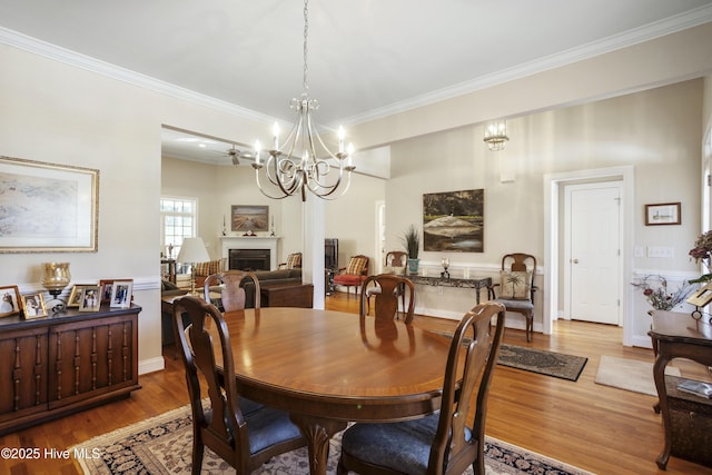 dining room with crown molding, a notable chandelier, a fireplace, and wood finished floors