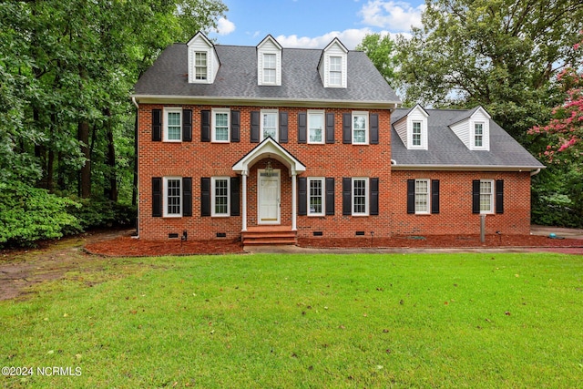 colonial inspired home with a shingled roof, crawl space, brick siding, and a front lawn