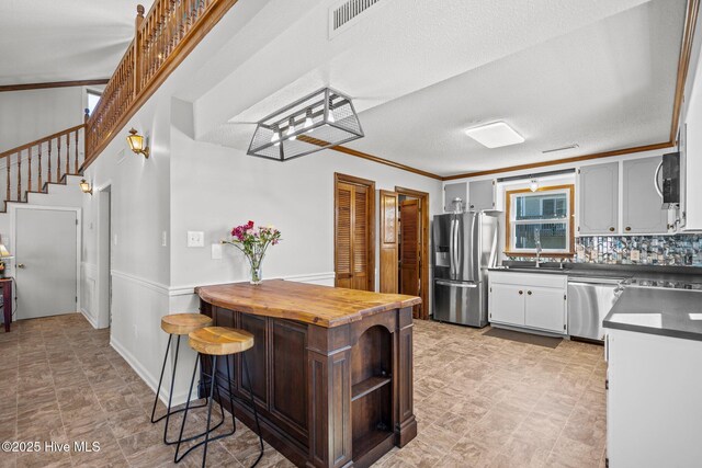 kitchen featuring stainless steel appliances, visible vents, a sink, and butcher block countertops