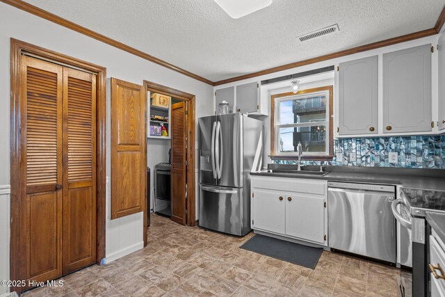 kitchen with stainless steel appliances, ornamental molding, dark countertops, and a peninsula