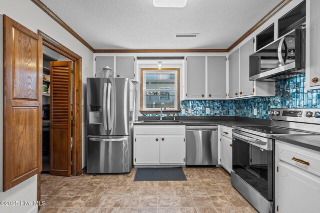 kitchen with visible vents, appliances with stainless steel finishes, a textured ceiling, crown molding, and a sink