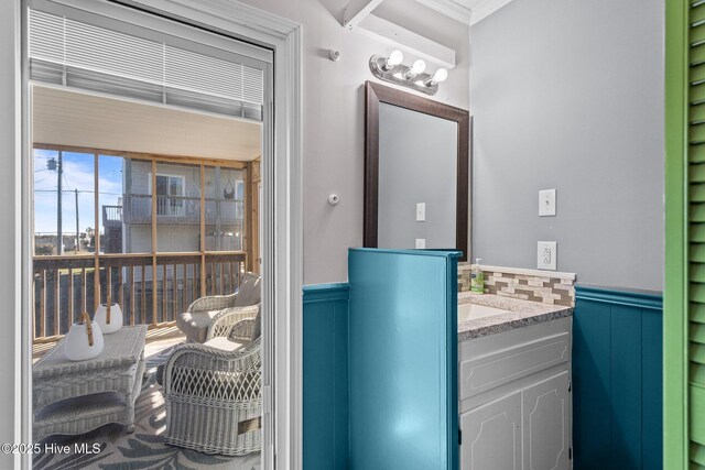 bathroom with a wainscoted wall, crown molding, and vanity