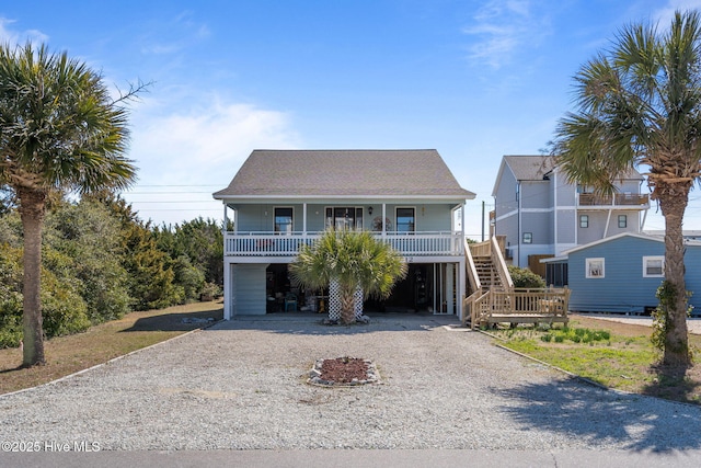 beach home featuring a carport, covered porch, driveway, and stairway