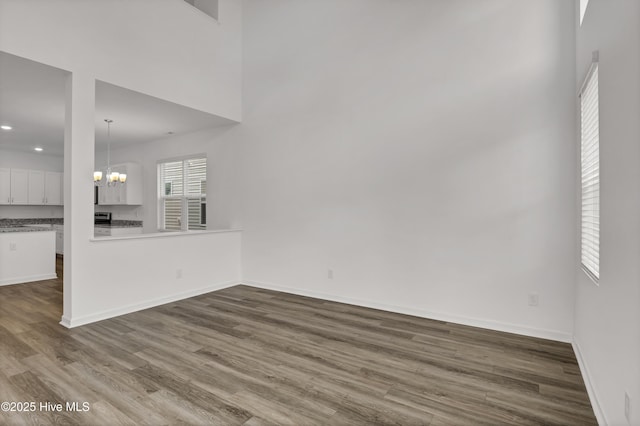 unfurnished living room featuring baseboards, a chandelier, dark wood finished floors, and recessed lighting