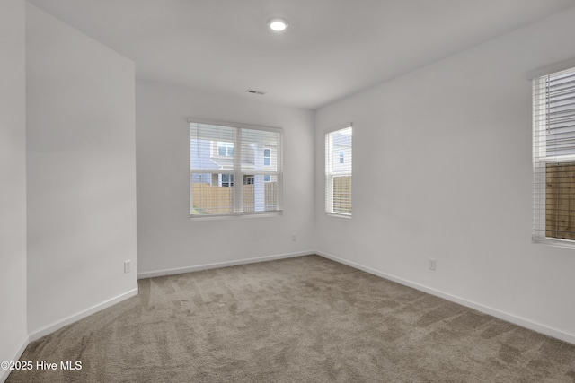 spare room featuring carpet floors, visible vents, and baseboards