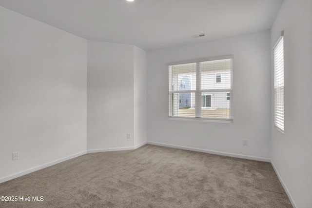 empty room featuring carpet, visible vents, and baseboards