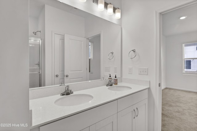 full bathroom featuring double vanity, a shower with door, baseboards, and a sink