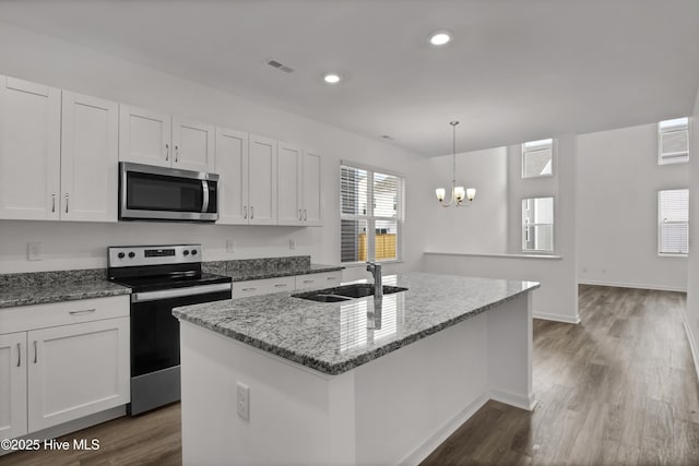 kitchen with stainless steel appliances, visible vents, white cabinetry, a sink, and light stone countertops