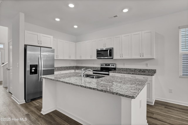 kitchen featuring appliances with stainless steel finishes, light stone counters, dark wood-style flooring, white cabinetry, and a sink