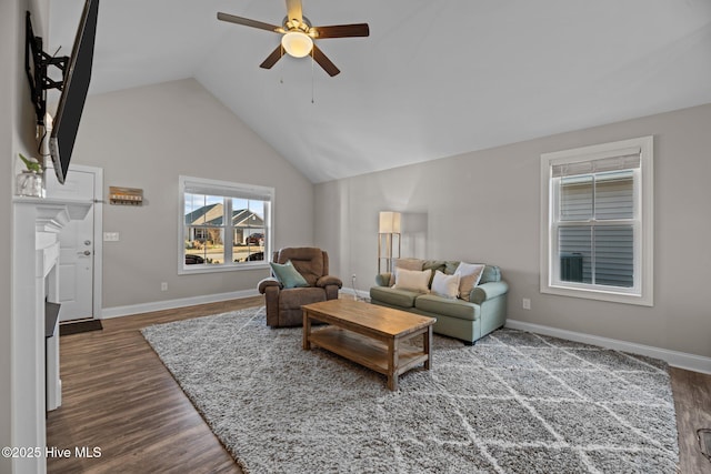 living area featuring dark wood-style floors, lofted ceiling, ceiling fan, and baseboards