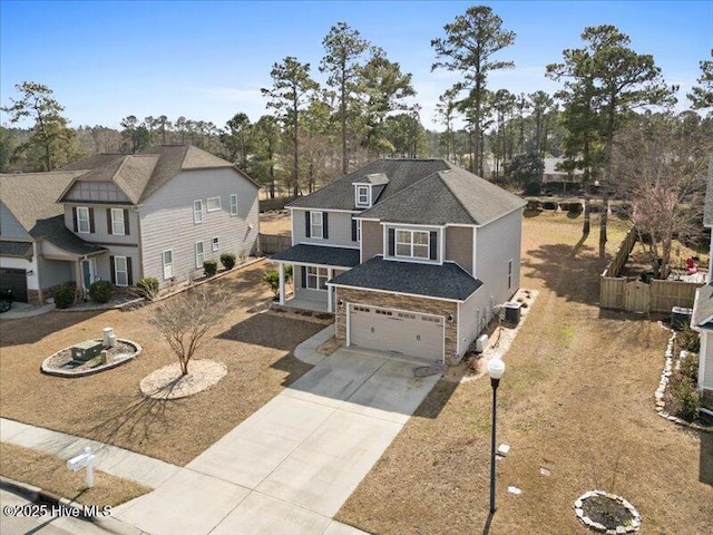 view of front of property featuring a garage, fence, concrete driveway, stone siding, and roof with shingles