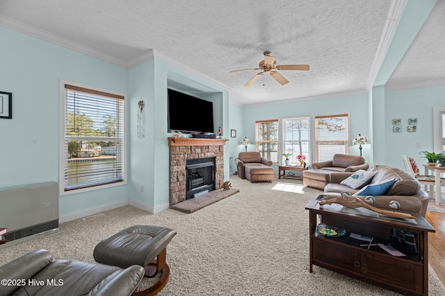 carpeted living room with a fireplace with raised hearth, a ceiling fan, heating unit, a textured ceiling, and crown molding