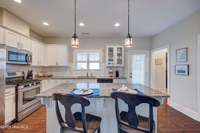 kitchen with a sink, visible vents, appliances with stainless steel finishes, backsplash, and a kitchen bar