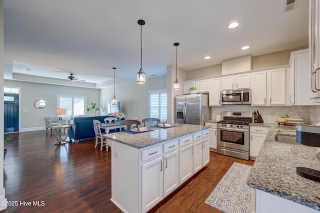 kitchen with stainless steel appliances, a kitchen island, visible vents, tasteful backsplash, and dark wood finished floors