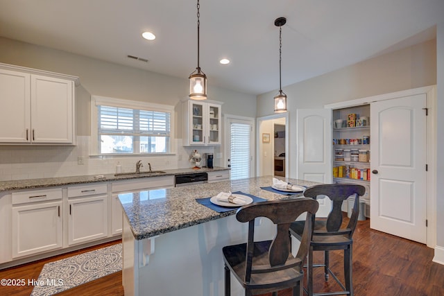 kitchen featuring visible vents, decorative backsplash, dark wood-type flooring, white cabinetry, and a sink