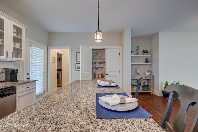 kitchen with dark wood-style floors, white cabinets, light stone countertops, dishwasher, and decorative light fixtures