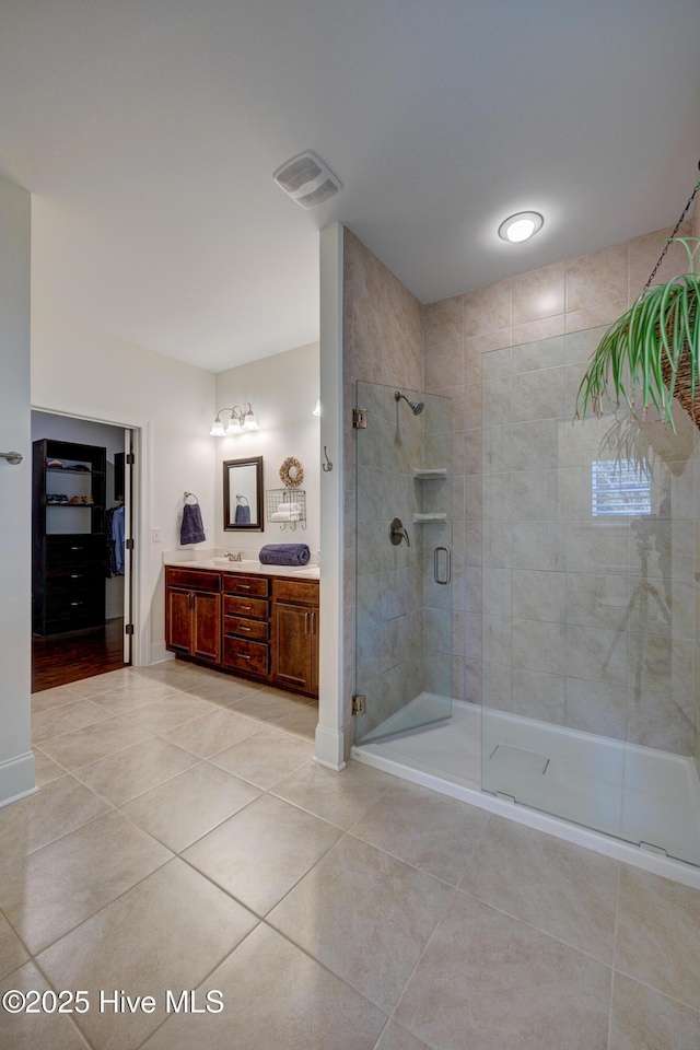 full bathroom with a stall shower, tile patterned flooring, visible vents, and double vanity