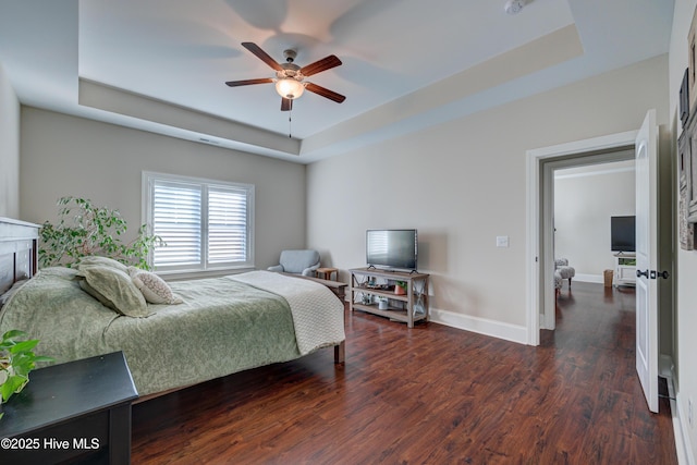 bedroom featuring wood finished floors, a raised ceiling, a ceiling fan, and baseboards