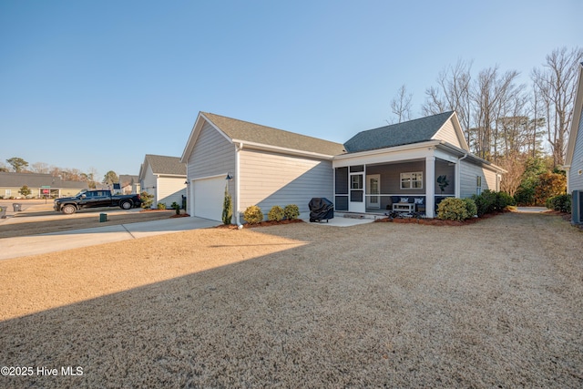 view of front of home featuring concrete driveway, an attached garage, cooling unit, and a sunroom