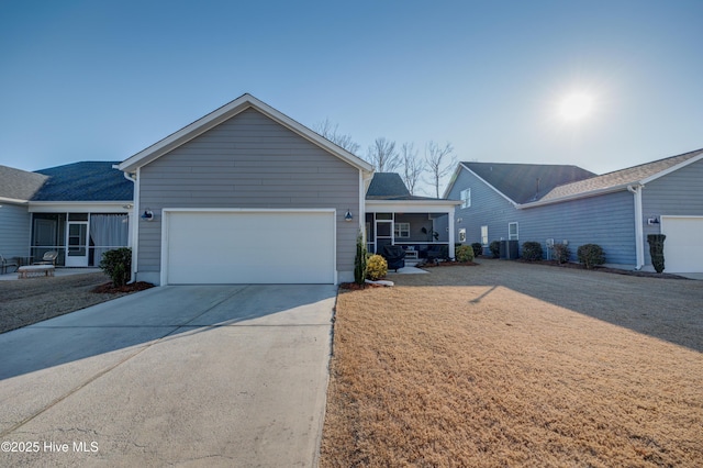 ranch-style house featuring a sunroom, an attached garage, and concrete driveway