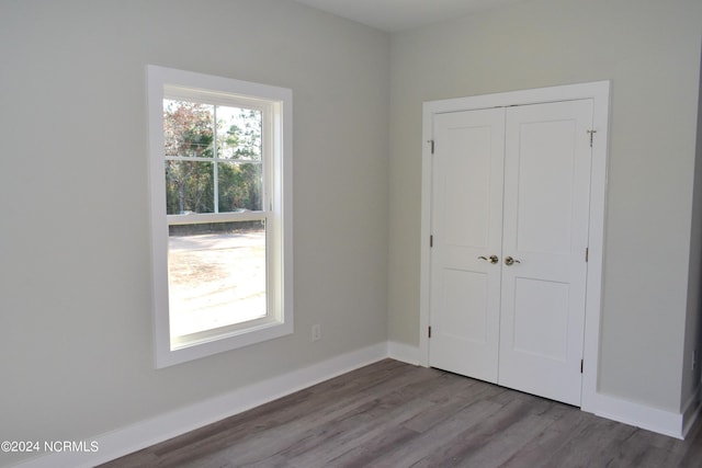 unfurnished bedroom with a closet, baseboards, and wood finished floors