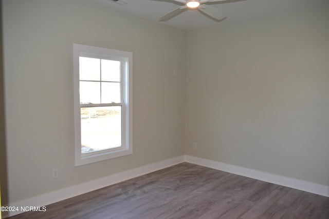 empty room featuring a ceiling fan, visible vents, baseboards, and wood finished floors