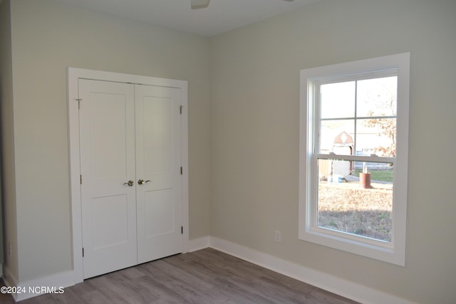 unfurnished bedroom with a closet, wood finished floors, and baseboards