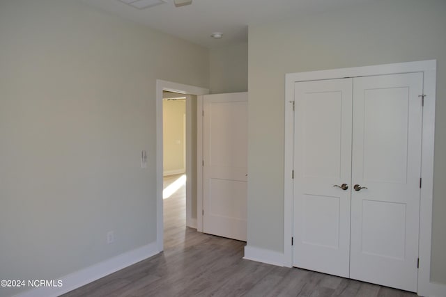 unfurnished bedroom with a closet, wood finished floors, and baseboards