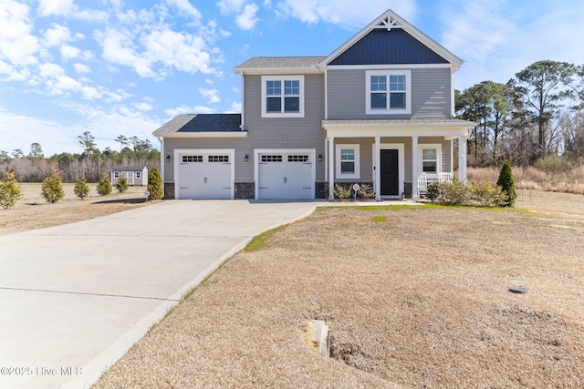 craftsman-style house with a garage, driveway, a porch, and stone siding