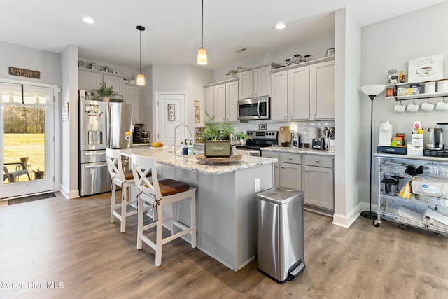 kitchen with stainless steel appliances, a breakfast bar, decorative backsplash, and wood finished floors