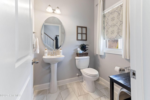 bathroom featuring marble finish floor, baseboards, and toilet